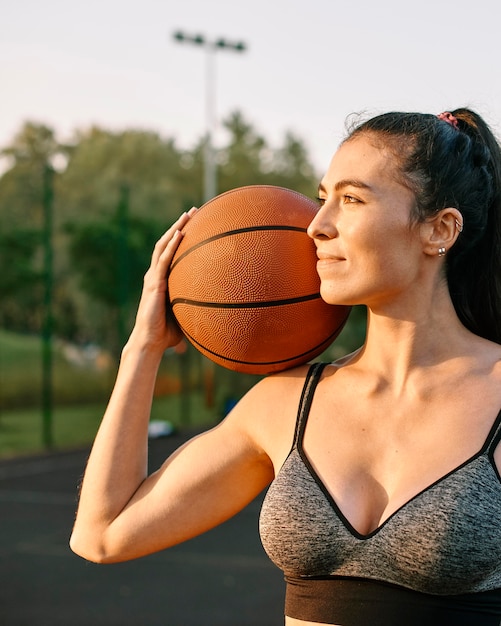 Giovane donna che gioca a basket da solo