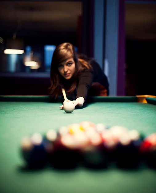 Free photo young woman playing billiard