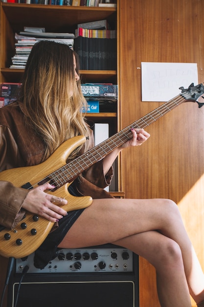 Young woman playing guitar on amplifier