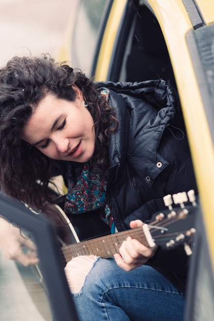 Young woman playing guitar in car