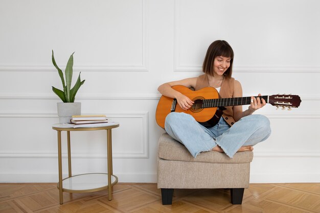 복사 공간이 있는 실내에서 기타를 연주하는 젊은 여성