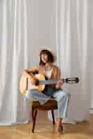 Free photo young woman playing guitar indoors