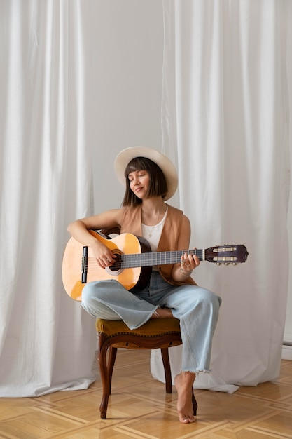 Молодая женщина играет на гитаре в помещении