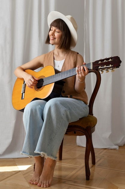 Молодая женщина играет на гитаре в помещении