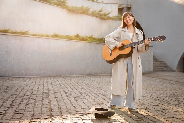 コピースペースで屋外でギターを弾く若い女性