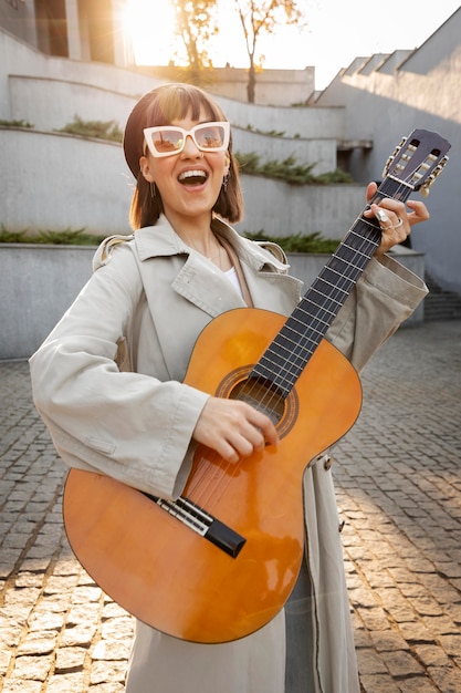 Бесплатное фото Молодая женщина играет на гитаре на открытом воздухе