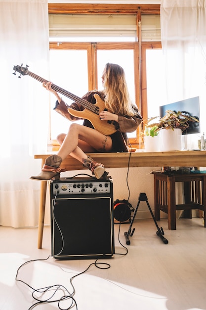 Foto gratuita giovane donna che suona la chitarra sul tavolo