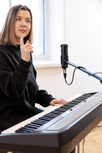 Young woman playing piano sitting in front of microphone