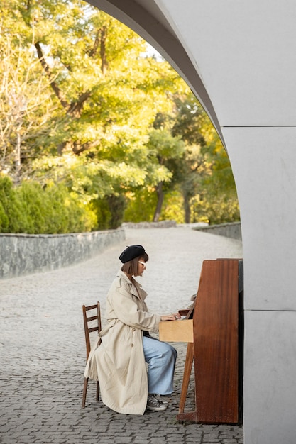 Бесплатное фото Молодая женщина играет на пианино на открытом воздухе с копией пространства