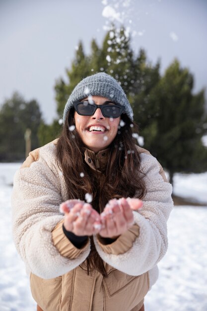 冬の旅行中に雪で遊ぶ若い女性