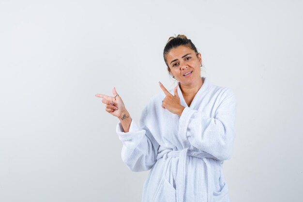 Young woman pointing aside in bathrobe and looking confident