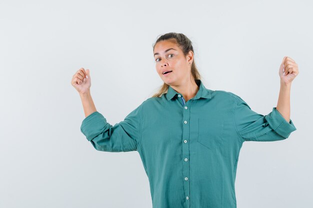 Young woman pointing back in blue shirt and looking interested