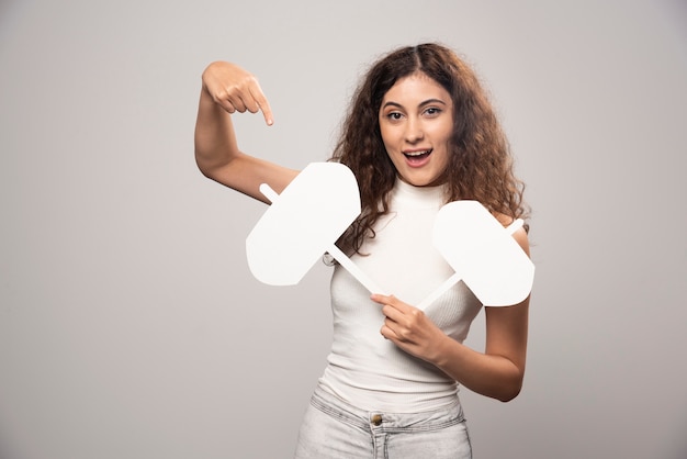 Young woman pointing at a blank white poster. High quality photo