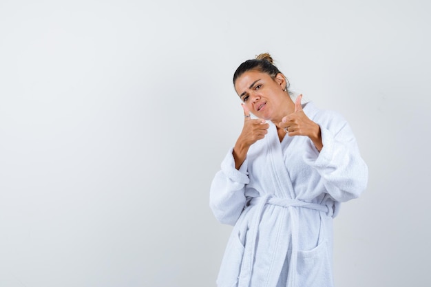 Free photo young woman pointing camera in bathrobe and looking joyful