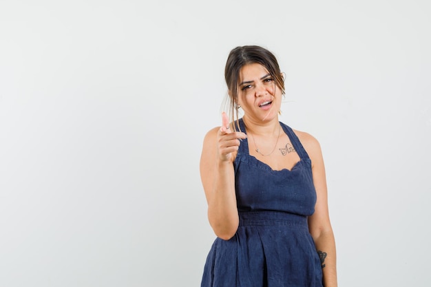 Young woman pointing at camera in dress and looking confident