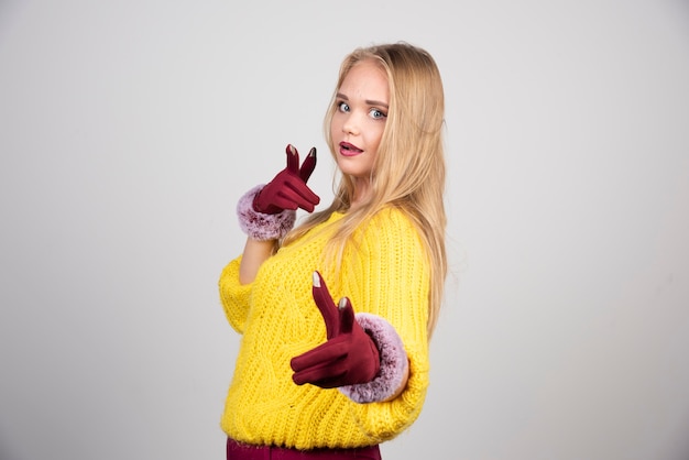 Young woman pointing at the camera with both hands .