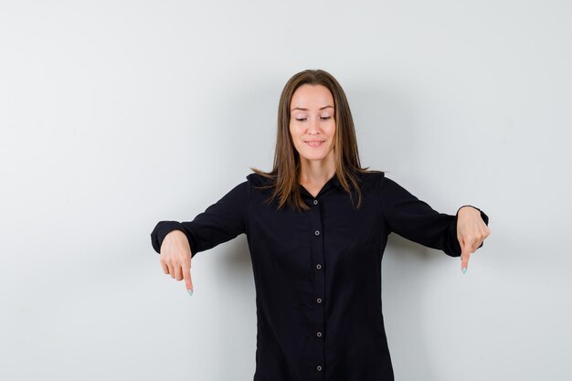 Young woman pointing down and looking cheerful