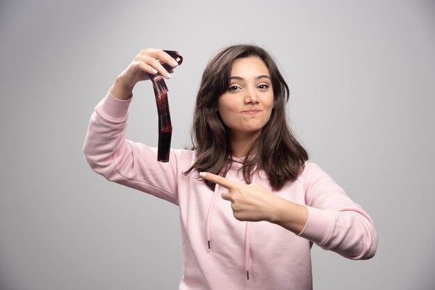 Young woman pointing at filmstrip on gray wall. 