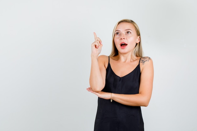 Young woman pointing finger up in black singlet and looking focused 