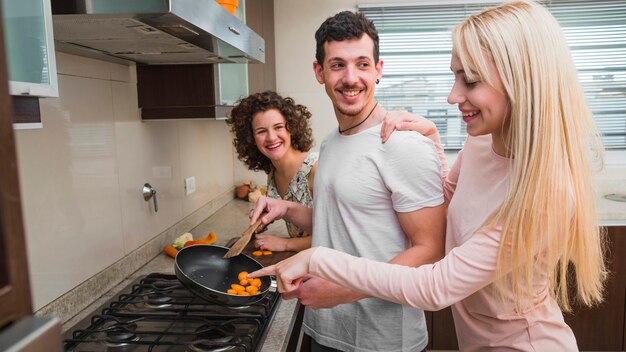 Young woman pointing at food prepared by her male friend