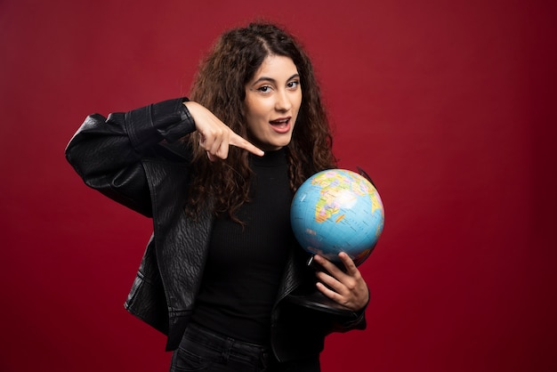 Young woman pointing at globe.