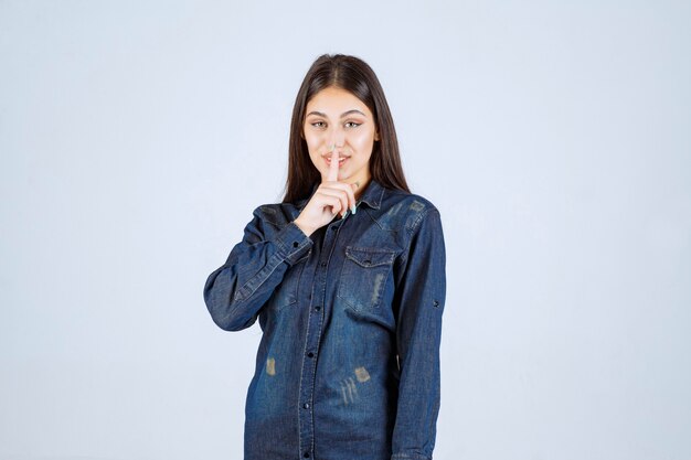 Young woman pointing her mouth and asking for silence