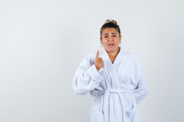 Young woman pointing herself in bathrobe and looking amazed