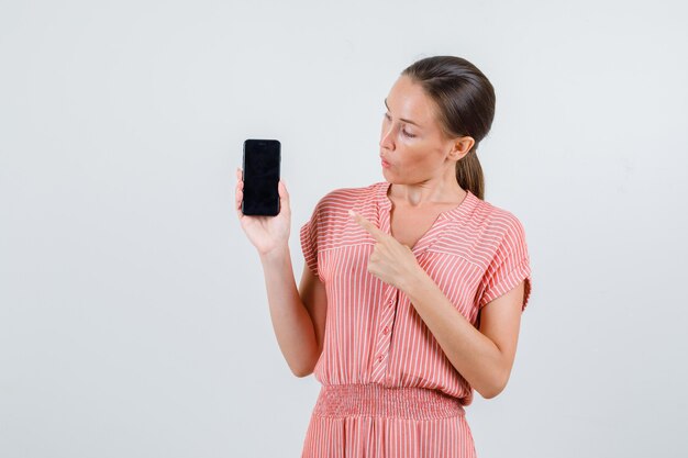縞模様のドレス、正面図で携帯電話を指している若い女性。