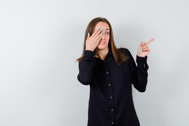 Young woman pointing right and covering eye