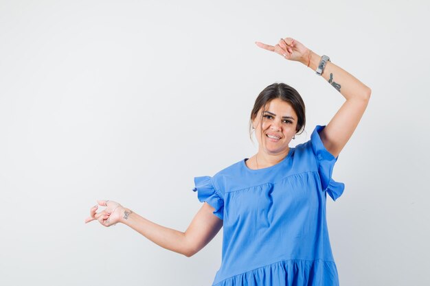 Young woman pointing to the side in blue dress and looking hopeful