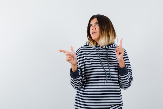 Young woman pointing something on the top and on the left on white background