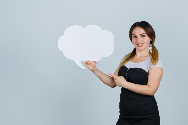 Free photo young woman pointing at speech bubble and looking joyful