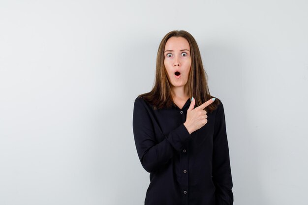 Young woman pointing up and looking shocked