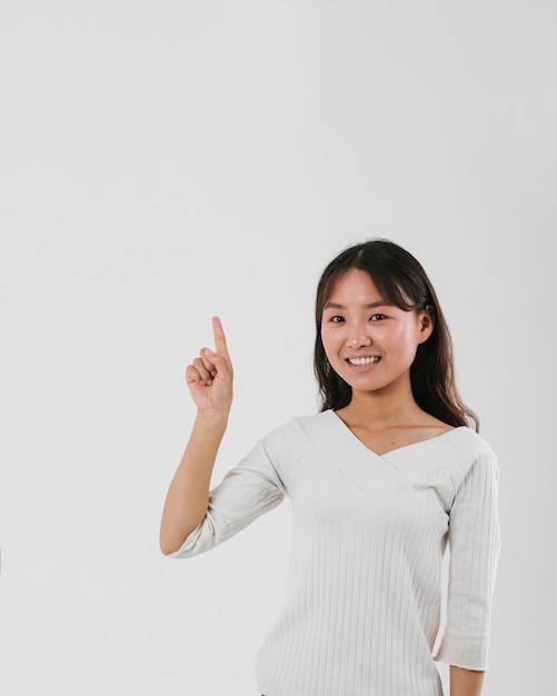 Young woman pointing up with copy space