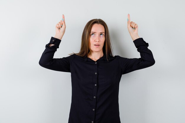 Young woman pointing up with index fingers