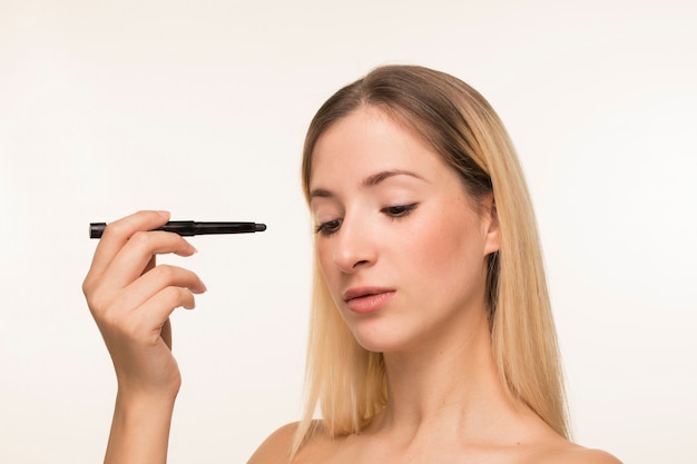 Free photo young woman pointing with eyeliner towards her face