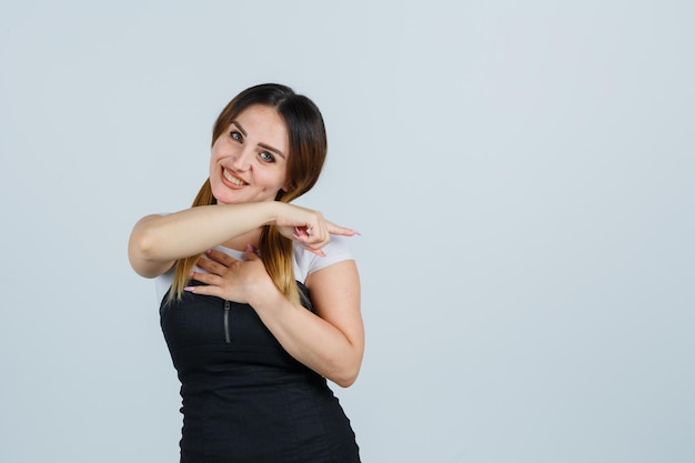 Young woman pointing with index finger and looking cheerful