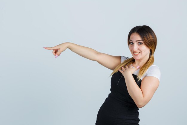 Young woman pointing with index finger and looking cheerful