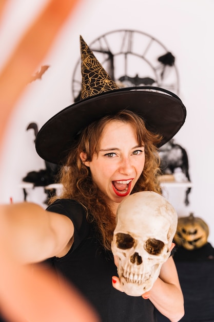 Young woman in pointy hat holding skull