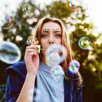 Free photo young woman portrait blowing soap bubbles