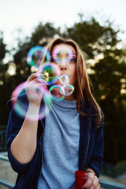 Молодая женщина, дует мыльные пузыри