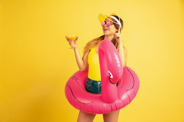 Young woman posing in beach ring with cocktail