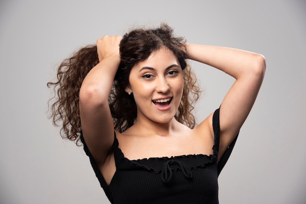 Young woman posing in black blouse with curly hair . High quality photo