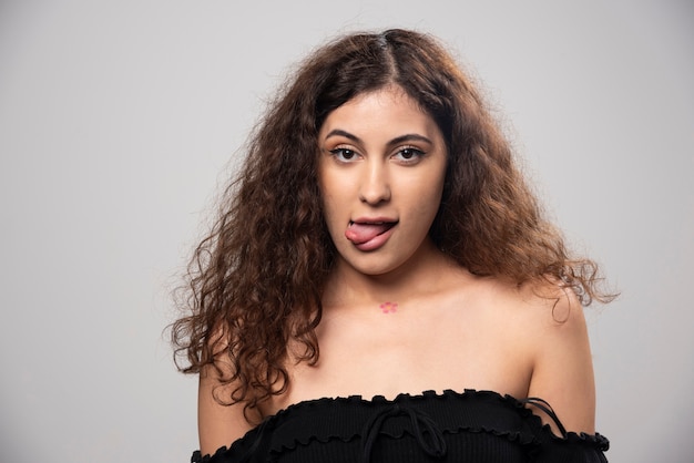 Young woman posing in black blouse with curly hair . High quality photo