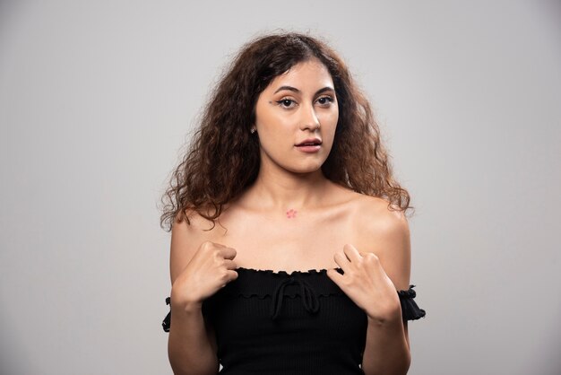 Young woman posing in black blouse with curly hair . High quality photo