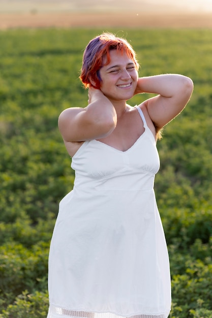 Young woman posing confidently outdoors in a field and showing armpit hair