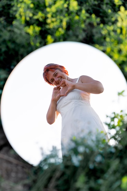 Young woman posing confidently outdoors using a round mirror