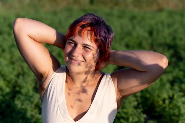 Young woman posing confidently and showing armpit hair