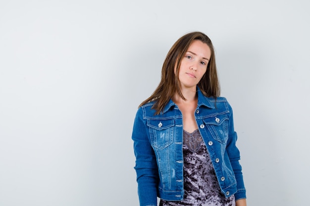 Young woman posing in denim jacket and looking sensible , front view.