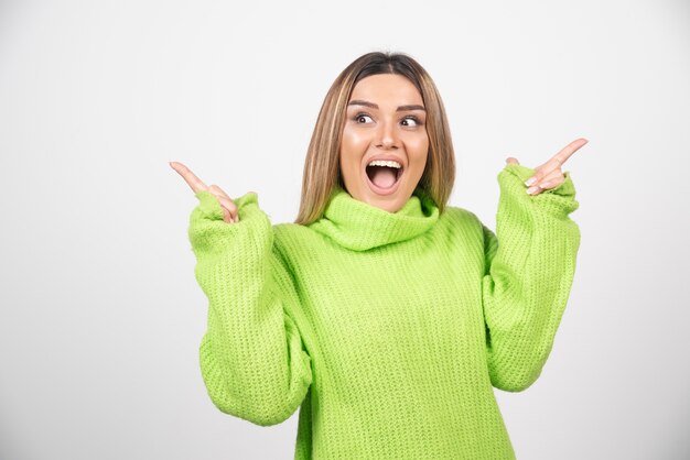 Free photo young woman posing in green t-shirt over a white wall.